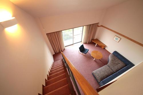 a room with a staircase and a chair and a table at B&B Forest Shima in Shima