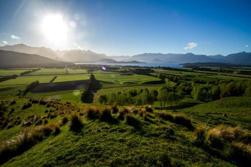 a field of grass with the sun in the background at Cabot Lodge - Fiordland National Park in Manapouri