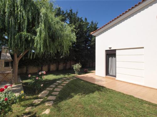 a backyard with a tree and a white building at Villa Rotunda A in Kolymvari