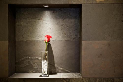 a red rose in a vase sitting on a shelf at UNAHOTELS Villa dei Platani Foligno in Foligno
