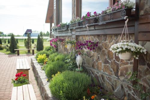 a garden with flowers and a stone wall at Hotel & Restaurant Complex HAP-OK in Brodki