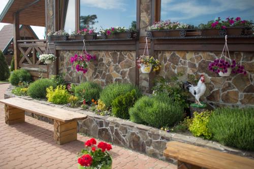 a garden with a chicken and a bench and flowers at Hotel & Restaurant Complex HAP-OK in Brodki