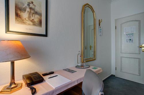 a desk with a phone and a lamp and a mirror at Hotel Arde Köln Zentrum in Cologne