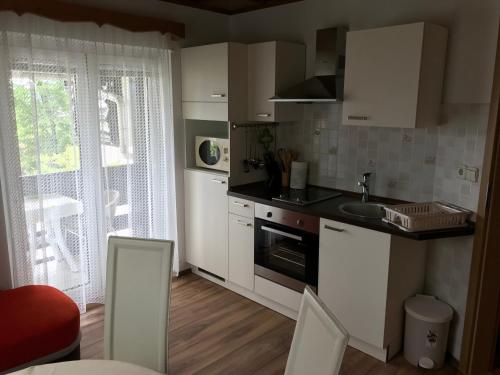 a kitchen with white cabinets and a sink and a window at Apartma Vražič in Bled
