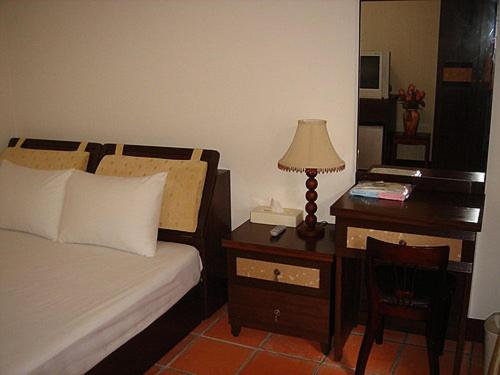 a bedroom with a bed and a desk with a lamp at Makung Traditional Homestay in Magong