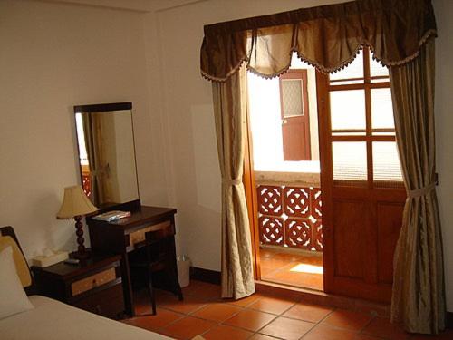 ein Schlafzimmer mit einer Tür, einem Schreibtisch und einem Fenster in der Unterkunft Makung Traditional Homestay in Magong