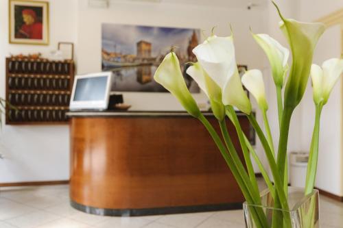 a vase with white flowers in front of a desk at Hotel Boccaccio-free parking- in Milano Marittima