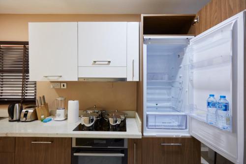 a kitchen with an open refrigerator with water bottles at Belanova Apartments and Suites in Abuja
