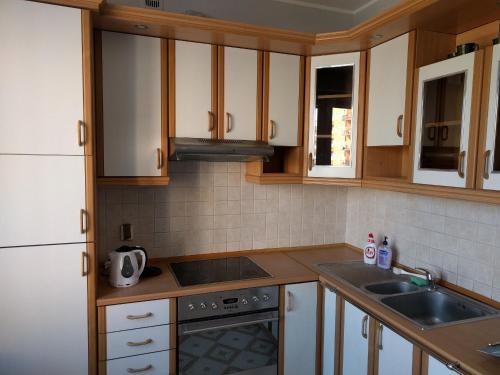 a kitchen with wooden cabinets and a sink and a stove at Apartament GRUBA RYBA in Gdynia