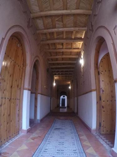 an empty hallway with wooden doors and a rug at Auberge des peupliers Café Restaurant in Akhendachou nʼAït Ouffi