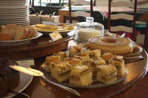 a table with a plate of bread and cakes on it at Pousada Villa Luna in Penedo