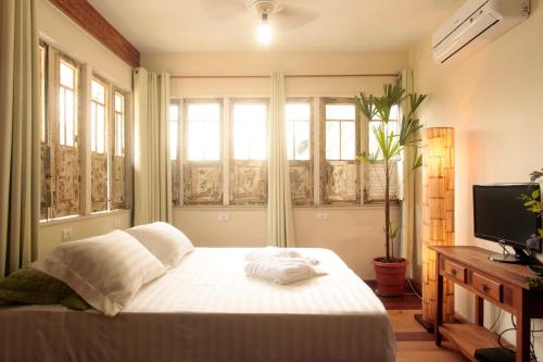 a bedroom with a bed and a tv and windows at Hotelinho Urca Guest House in Rio de Janeiro