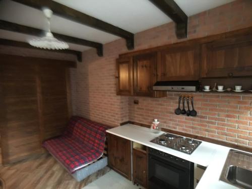 a kitchen with wooden cabinets and a brick wall at Il Capriolo in Sauze dʼOulx
