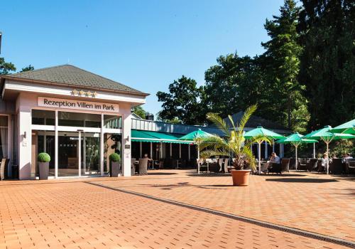 un edificio con tavoli e ombrelloni in un cortile di Ostseehotel Villen im Park - ein Rovell Hotel a Bansin