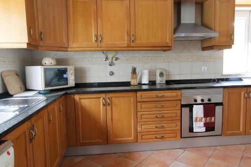 a kitchen with wooden cabinets and a microwave at Villa Monte da Alfarrobeira in Estói
