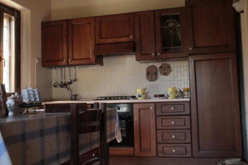 a kitchen with wooden cabinets and a stove top oven at Case Vacanza S. Nicola in Viggianello