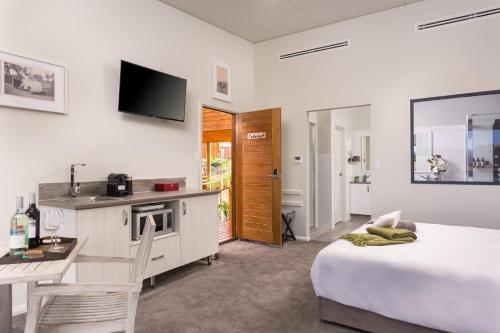 a hotel room with a bed and a desk and a kitchen at The Swan Valley Retreat in Henley Brook