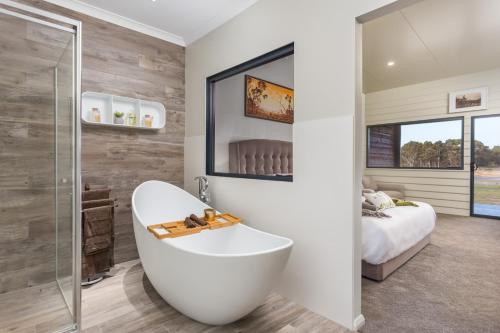 a bathroom with a white tub and a bedroom at The Swan Valley Retreat in Henley Brook