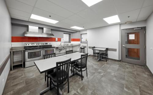 Residence & Conference Centre - King City في King City: مطبخ مع طاولات وكراسي في الغرفة
