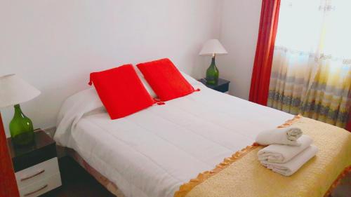 1 dormitorio con 1 cama con almohadas y toallas rojas en La Casa de Reyes Posada in 