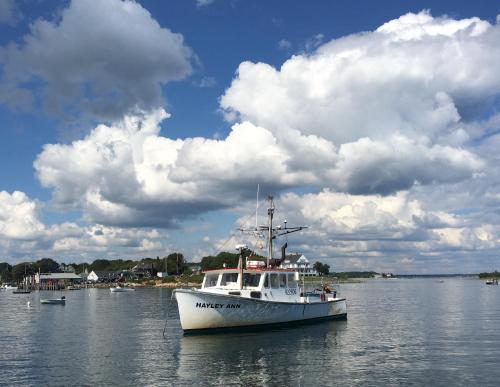 a white boat in the water under a cloudy sky at Rhumb Line Resort in Kennebunkport