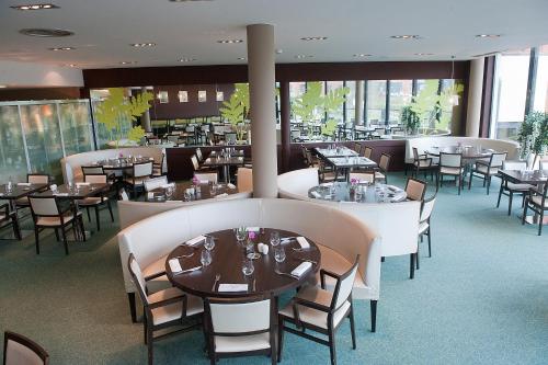 - une salle à manger avec des tables, des chaises et des fenêtres dans l'établissement Hôtel Le Palladior Voiron, à Voiron
