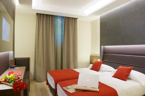 a hotel room with two beds and a laptop on a table at UNAHOTELS Villa dei Platani Foligno in Foligno