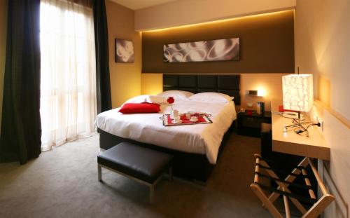 a hotel room with a bed with a tray of food on it at UNAHOTELS Villa dei Platani Foligno in Foligno