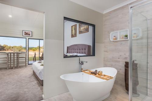 a white bathroom with a tub and a bedroom at The Swan Valley Retreat in Henley Brook