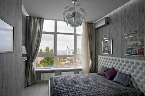 a bedroom with a bed and a large window at Beach & Beatles Apartments in Odesa