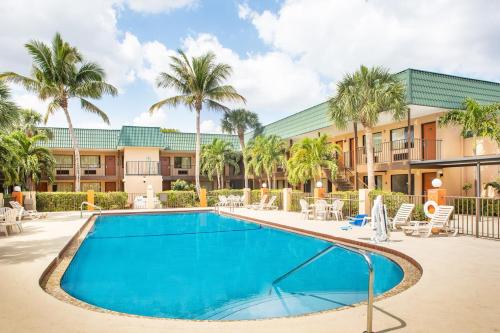 a swimming pool in front of a building with palm trees at Super 8 by Wyndham North Palm Beach in North Palm Beach
