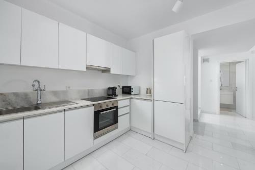 a white kitchen with white cabinets and a sink at Maria & Nada Beachfront Villas in Kolimbia