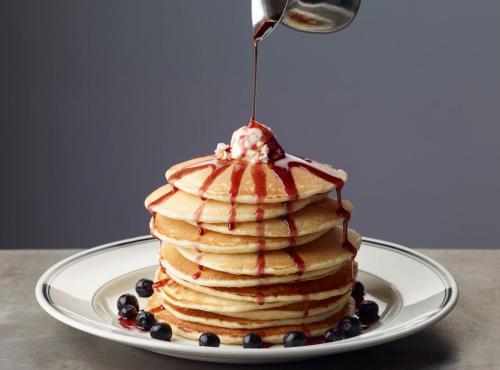 a stack of pancakes with syrup and blueberries on a plate at The Georgetown Inn in Washington