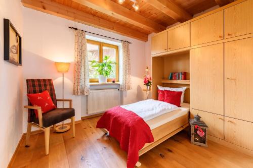 1 dormitorio con 1 cama, 1 silla y 1 ventana en "Viktoria Chalet" - Annehmlichkeiten vom 4-Sterne Familien-und Wellnesshotel Viktoria nebenan können mitbenutzt werden, en Oberstdorf