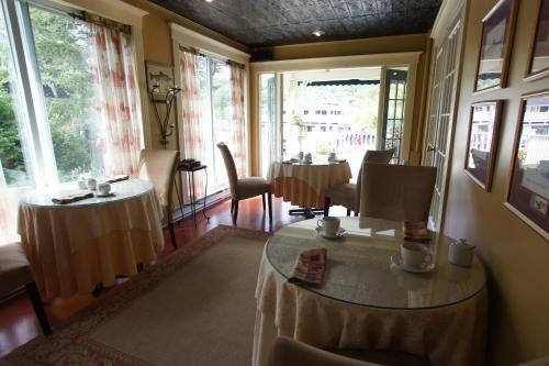 a room with a table and chairs and windows at Serendipity B&B in North Hatley