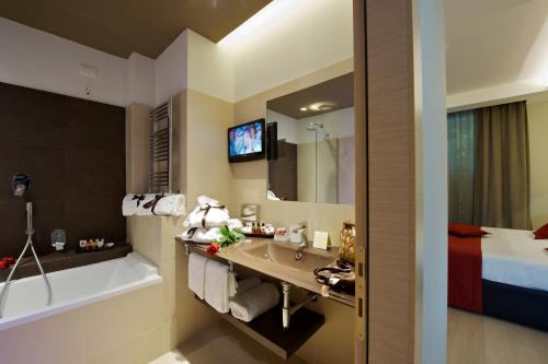 a bathroom with a sink and a tub and a bed at UNAHOTELS Villa dei Platani Foligno in Foligno