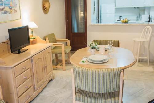 sala de estar con mesa y TV en Jardín de Mariote Apartment, en Almuñécar