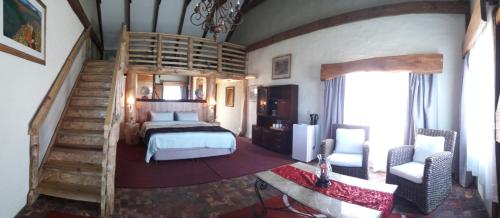 a bedroom with a bed and a spiral staircase at TNiqua Stable Inn in Plettenberg Bay
