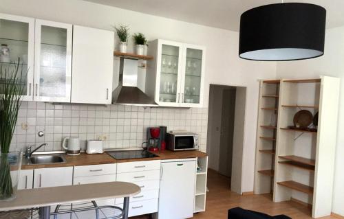 eine Küche mit weißen Schränken, einer Spüle und einer Mikrowelle in der Unterkunft Odessa in Köln