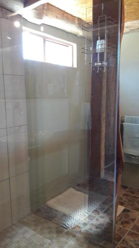 a glass shower in a bathroom with a window at TNiqua Stable Inn in Plettenberg Bay