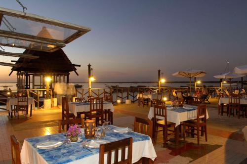 a restaurant with tables and chairs and the ocean at Hôtel Kadiandoumagne in Ziguinchor