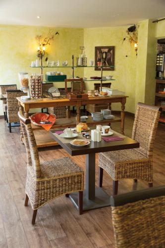 a dining room with a table and wicker chairs at Contact Hôtel Le Relais de Vellinus in Beaulieu-sur-Dordogne