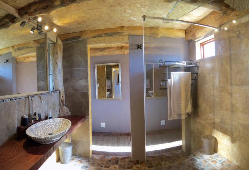 a large bathroom with a sink and a shower at TNiqua Stable Inn in Plettenberg Bay