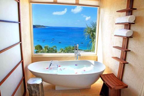 a bath tub in a room with a large window at CeBlue Villas in The Valley