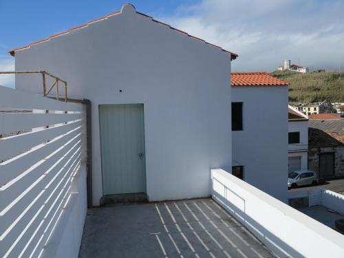a white building with a door on a balcony at Baía das Caldeirinhas in Horta
