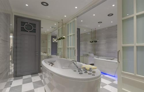 a white bathroom with a tub and a bath tub at Boutique Hotel Corso in Karlovy Vary