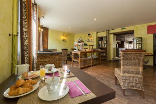 a dining room with a table with food on it at Contact Hôtel Le Relais de Vellinus in Beaulieu-sur-Dordogne