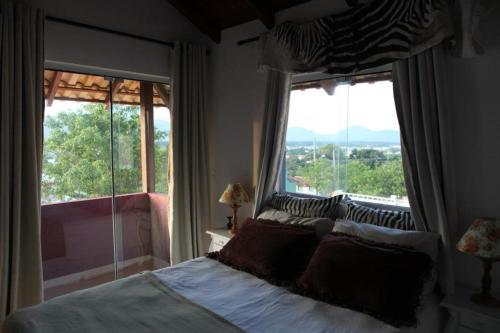 um quarto com uma cama e uma grande janela em Pousada Pedra da Boa Vista em Florianópolis