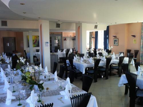 a room filled with tables and chairs with white tablecloths at La Maison ERNENWEIN in Obermodern