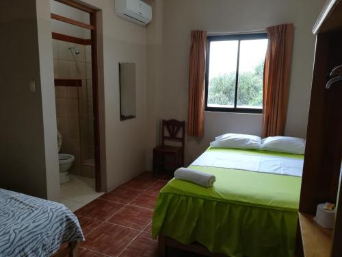 ein Schlafzimmer mit 2 Betten und ein Bad mit einem Fenster in der Unterkunft Hospedaje el Emperador in Pucallpa